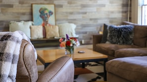 A living room with a sofa, armchair, and a coffee table with a vase of flowers.