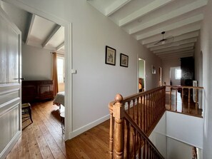 Ein geräumiges Zimmer mit Holzboden, einer Holztreppe und Blick auf einen Essbereich.