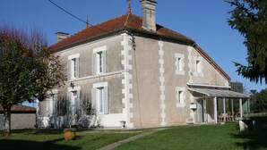 A two-story building with a red-tiled roof, a covered porch, and a well-maintained lawn. - 3* family house, sleeps 9, ideal for a quiet vacation with family and friends (Rouffignac)