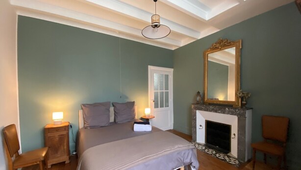 A bedroom with a bed, bedside tables, a mirror, a fireplace, and a door. - 3* family house, sleeps 9, ideal for a quiet vacation with family and friends (Rouffignac)