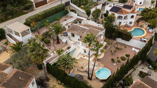Una propiedad residencial con piscina, terraza techada y un pequeño jardín.