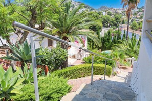 A staircase with metal handrails, surrounded by lush greenery and a view of a hillside with buildings. - CostaBlancaDreams - Villa Orquidia in Benissa (Benissa)