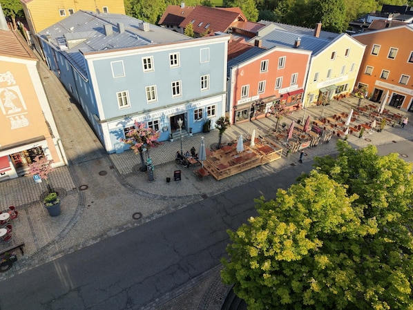 Un hĂŽtel Ă la façade bleue, dotĂ© dâun espace extĂ©rieur amĂ©nagĂ© et situĂ© dans une rue pavĂ©e.