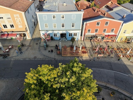 A hotel with a central courtyard, outdoor seating, and a large tree in the foreground.. Hotel Zum Kellermann