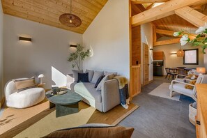 Ein modernes Interieur mit einer Couch, Sesseln, einem Couchtisch und einem Essbereich.