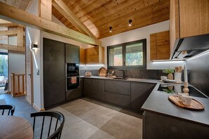 Eine moderne Küche mit Holzbalken, integrierten Geräten und einem großen Fenster.