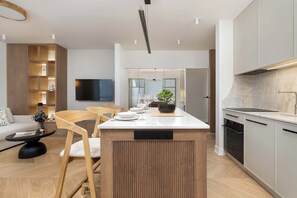Uma cozinha moderna com uma ilha central, eletrodomésticos embutidos e uma área de jantar com mesa e cadeiras redondas.