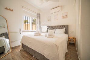 Ein Schlafzimmer mit einem Bett, einem Spiegel, einem Fenster und einer Wand-Klimaanlage.