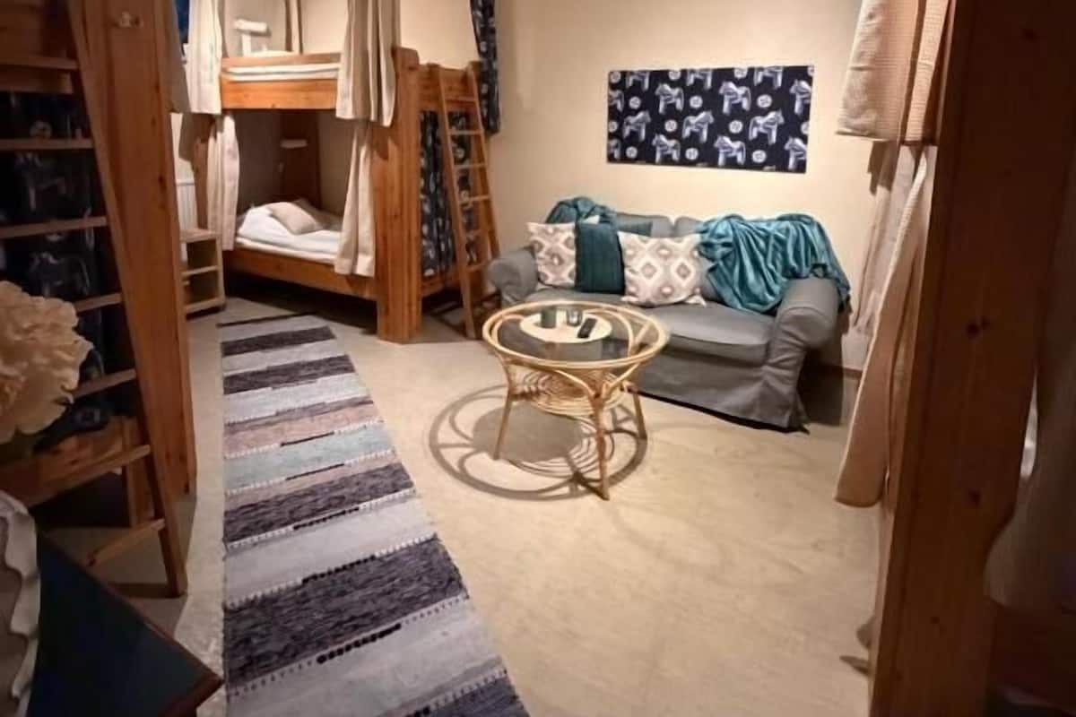 A room with bunk beds, a small round table, a sofa, and a patterned rug.