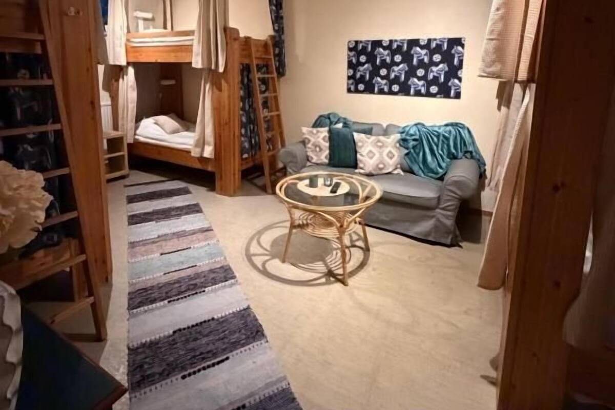 Um quarto com beliches, uma pequena mesa redonda, um sofá e um tapete estampado.