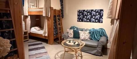 A room with bunk beds, a small round table, a sofa, and a patterned rug.
