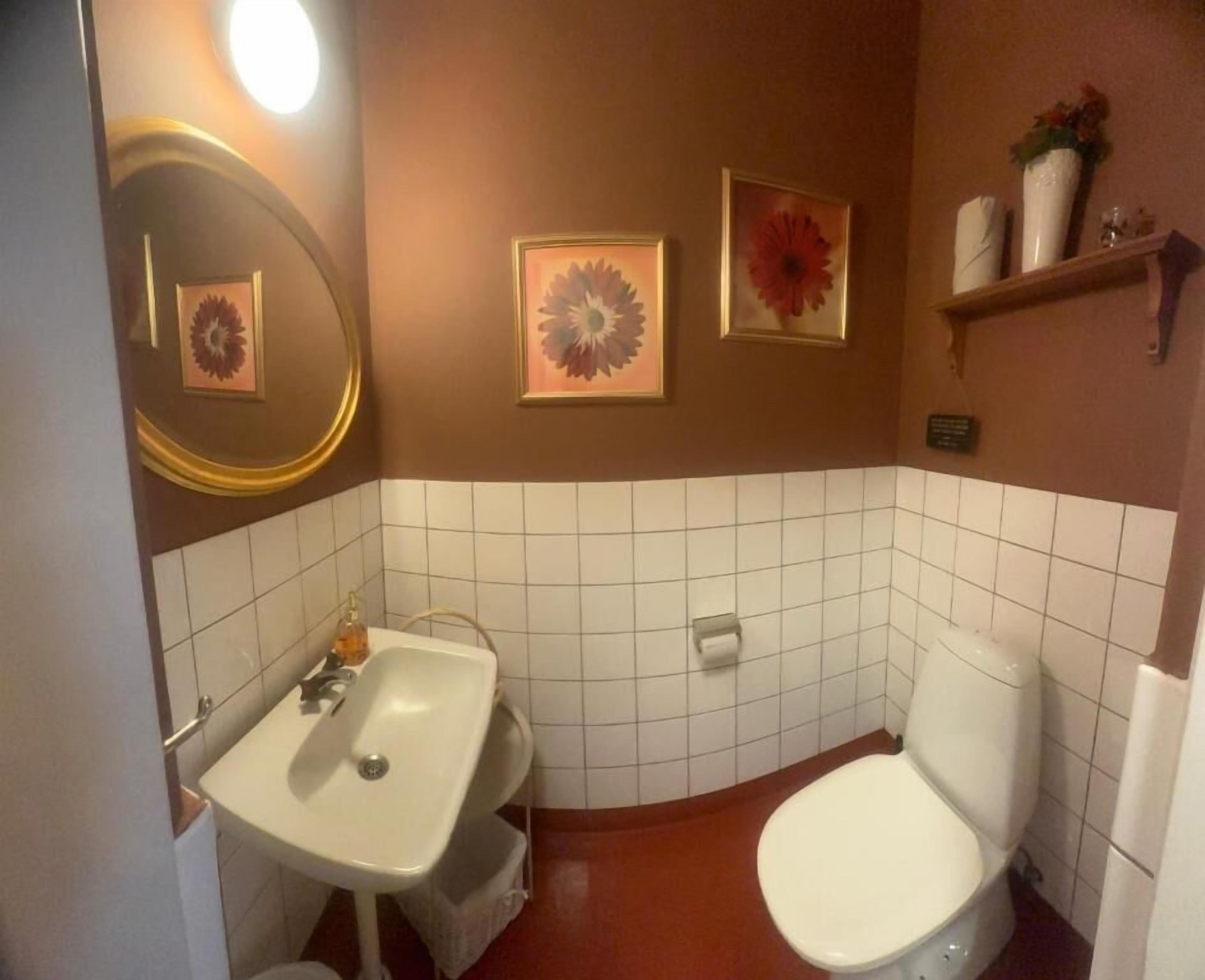 A bathroom with a sink, toilet, and two framed floral pictures on the wall.