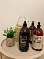 Tres botellas de productos para el cuidado del cabello sobre una mesa redonda.