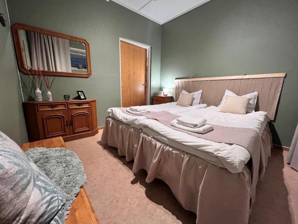 Quarto com cama, penteadeira, espelho e porta.