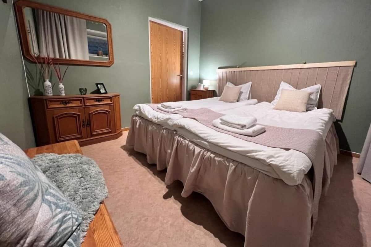A bedroom with a bed, a dresser, a mirror, and a door.
