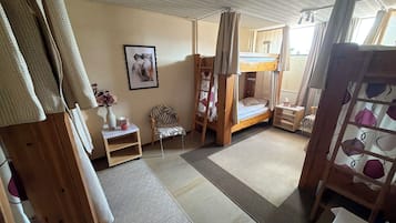 Una habitación con una cama individual, una silla, una mesita y un cuadro en la pared.