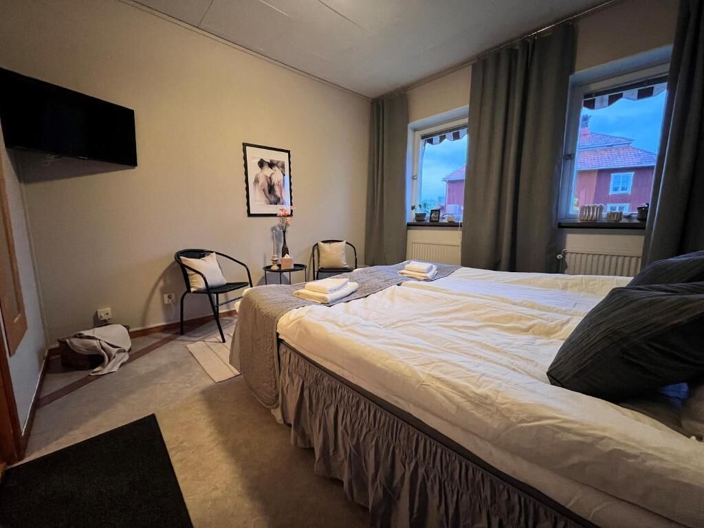 Quarto com uma cama, uma cadeira, uma escrivaninha, uma televisão e uma janela.