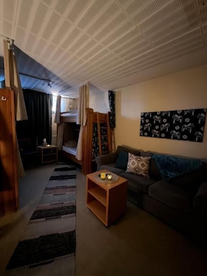 Una sala de estar acogedora con un sofá, una mesa de centro, una cama nido y una pared con un diseño estampado.