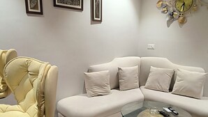 A modern living room with a sectional sofa, a round glass coffee table, and a yellow armchair.