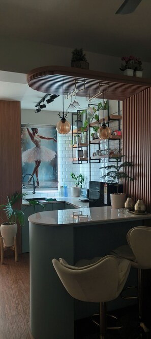 Cocina moderna con una isla central, taburetes de bar, iluminación colgante y un cartel grande de una bailarina de ballet.