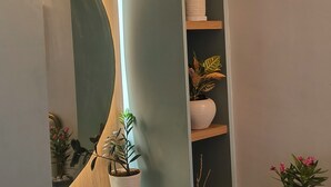 A modern room with a built-in mirror, wooden shelves with potted plants, and a small round table with a decorative item.