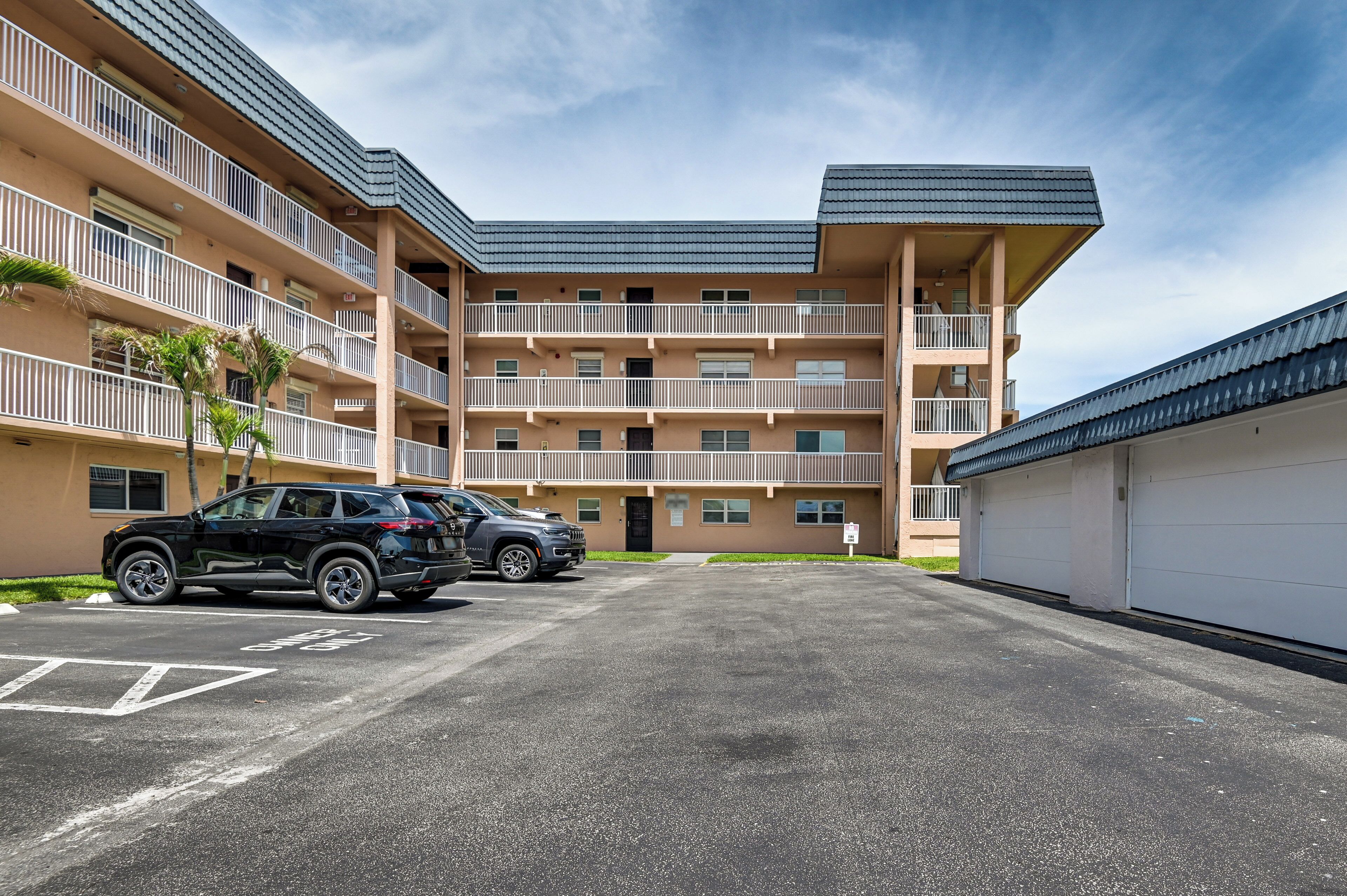 En byggnad med flera våningar, en parkeringsplats, en svart SUV och en vit garageport.