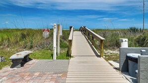 Ein hölzerner Steg führt zum Strand, mit einem Schild, das ein Parkverbot am Strand anzeigt.