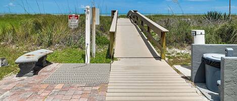 A wooden boardwalk leading to a beach, with a sign indicating no parking on the beach.