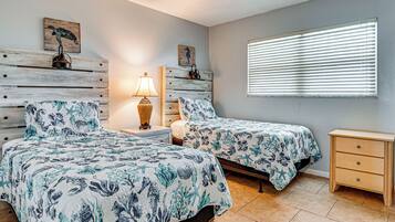 Un dormitorio con dos camas, una mesita de noche, una lámpara, un aparador de madera y obras de arte en las paredes.