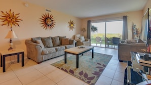 A living room with a sofa, a coffee table, and a TV stand. - Enjoy the Pool & Beach! Cocoa Beach Condo (Cocoa Beach)