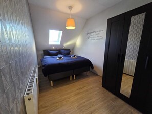 Een slaapkamer met een bed, een raam, een plafondlamp en een garderobe.