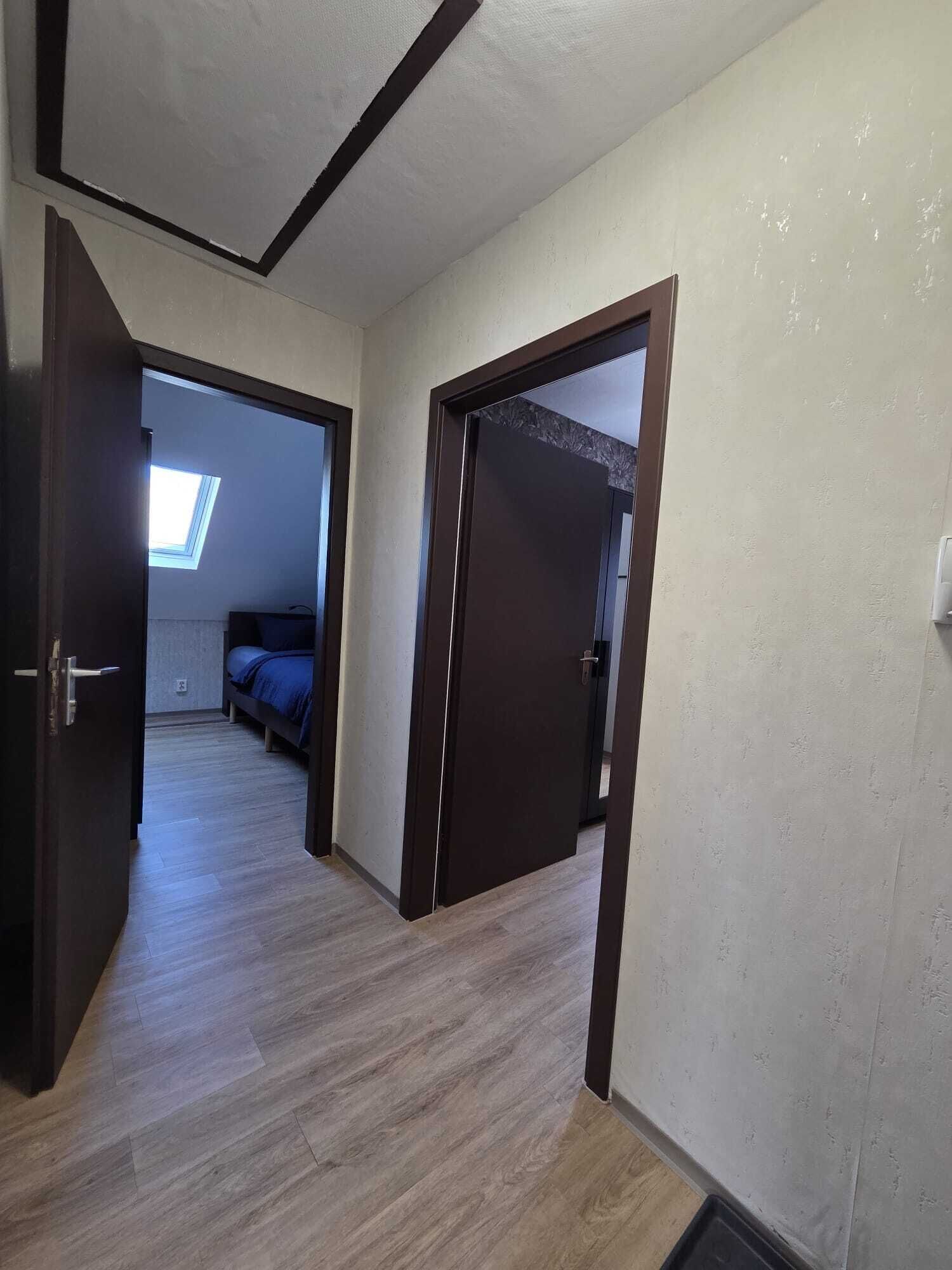 A hallway leading to a bedroom with a skylight, a bed, and a door.