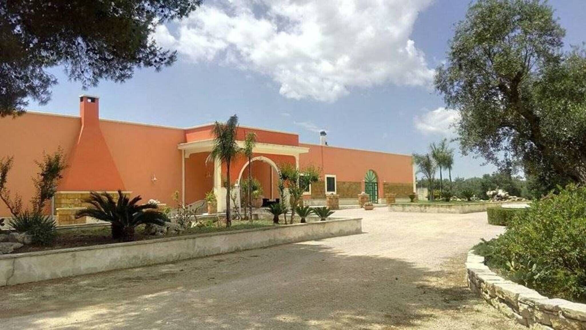 Un edificio de fachada roja, entrada de arco y camino de entrada pavimentado.