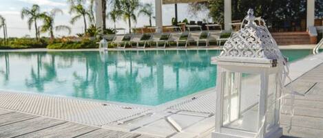 A pool with clear water, surrounded by lounge chairs and a decorative lantern.