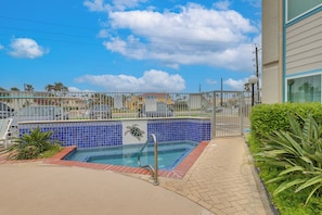 Ein Swimmingpool mit blau gefliestem Rand, einer Metallleiter und einem Metallzaun darum.