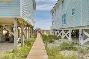 A wooden boardwalk leading to beach houses with a sandy beach and dunes in the background. - Walk to Beach! Water-view Home in Gulf Shores (Gulf Shores)