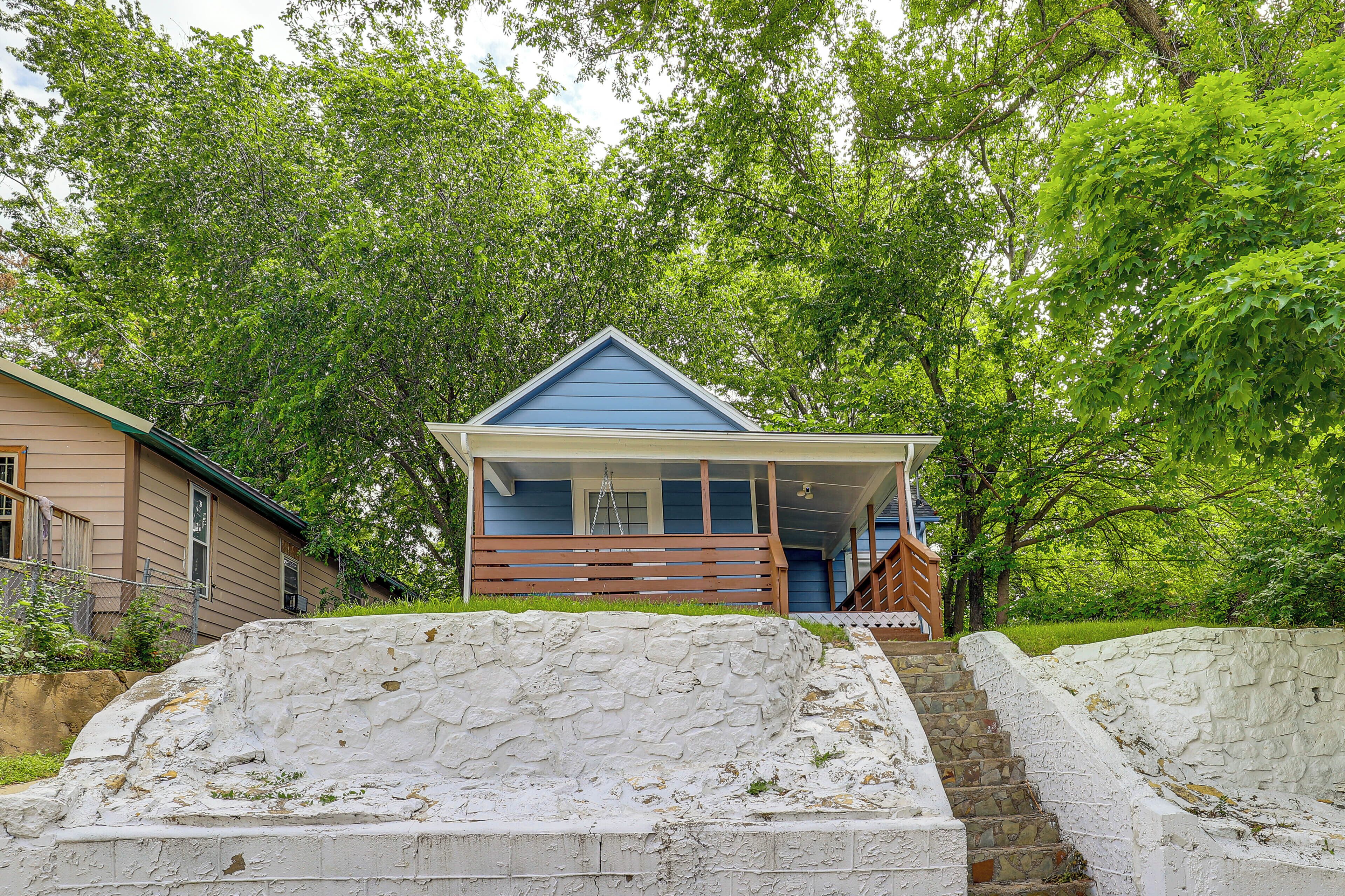 Een huis met een blauw dak, een veranda en een stenen trap naar de voordeur.