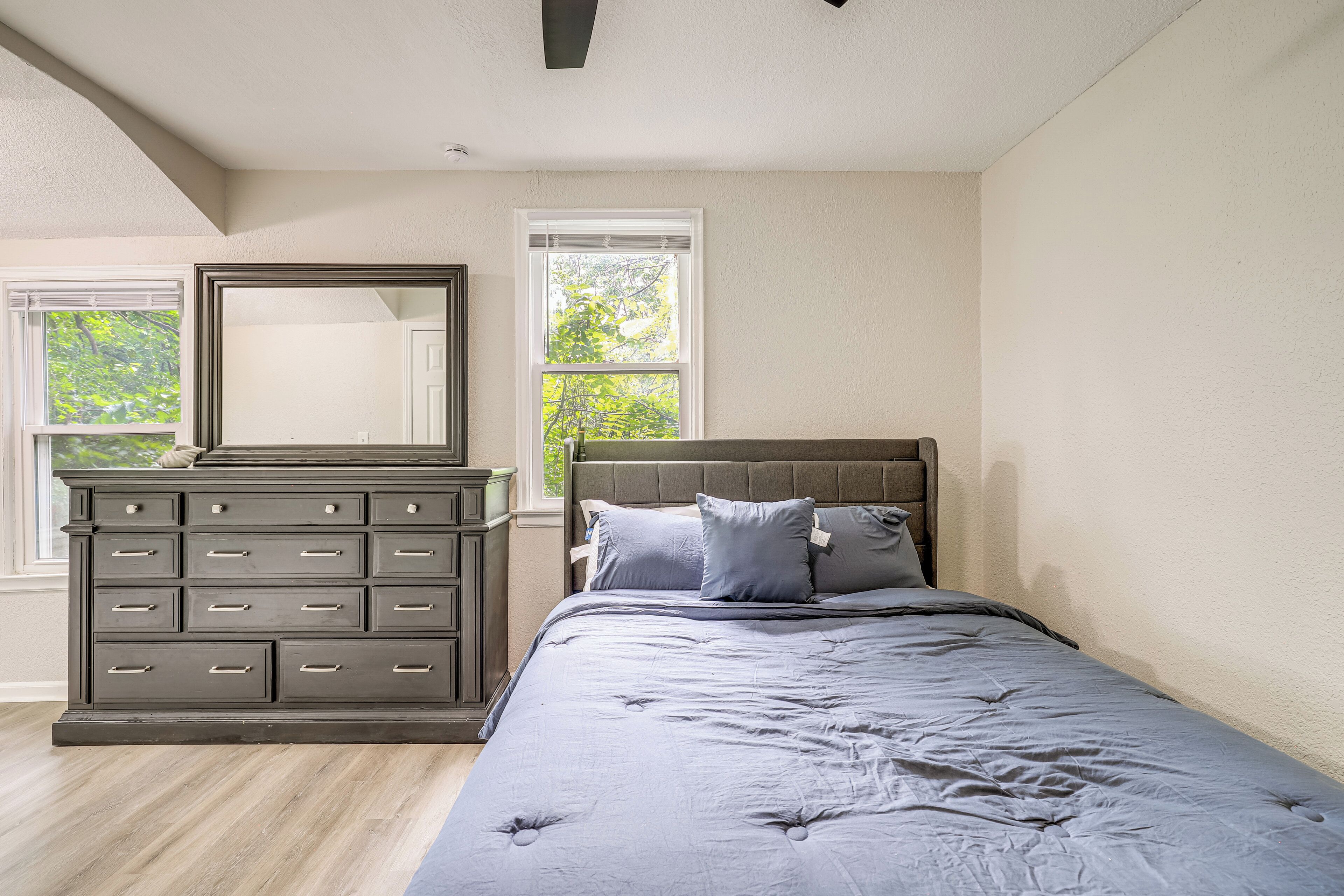 Une chambre à coucher avec un lit, une commode et deux fenêtres.