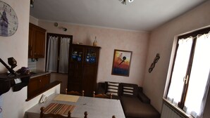 A compact living space with a dining table, chairs, a sofa, a cabinet, and a window with curtains. - Comfortable and welcoming apartment (Anghiari)