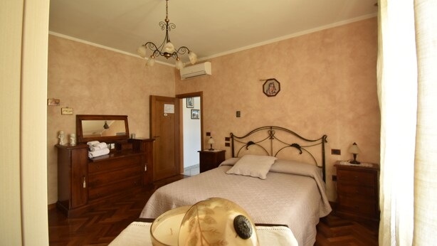 A bedroom with a bed, dresser, nightstand, and a chandelier. - Comfortable and welcoming apartment (Anghiari)