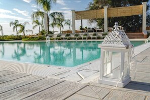 Une piscine à l’eau claire, entourée de chaises longues et agrémentée d’une lanterne décorative.