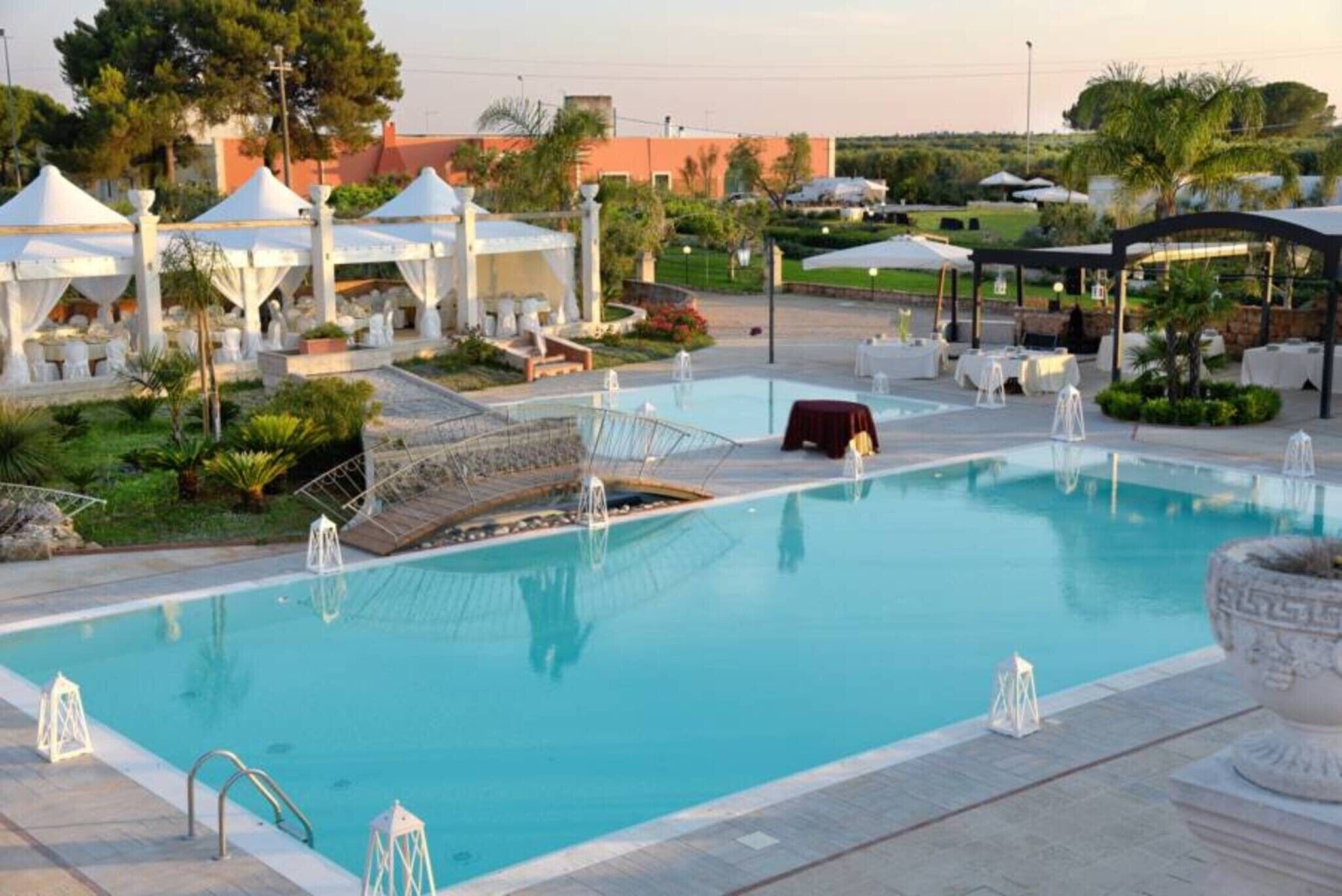 A swimming pool with a bridge, lounge chairs, and umbrellas.