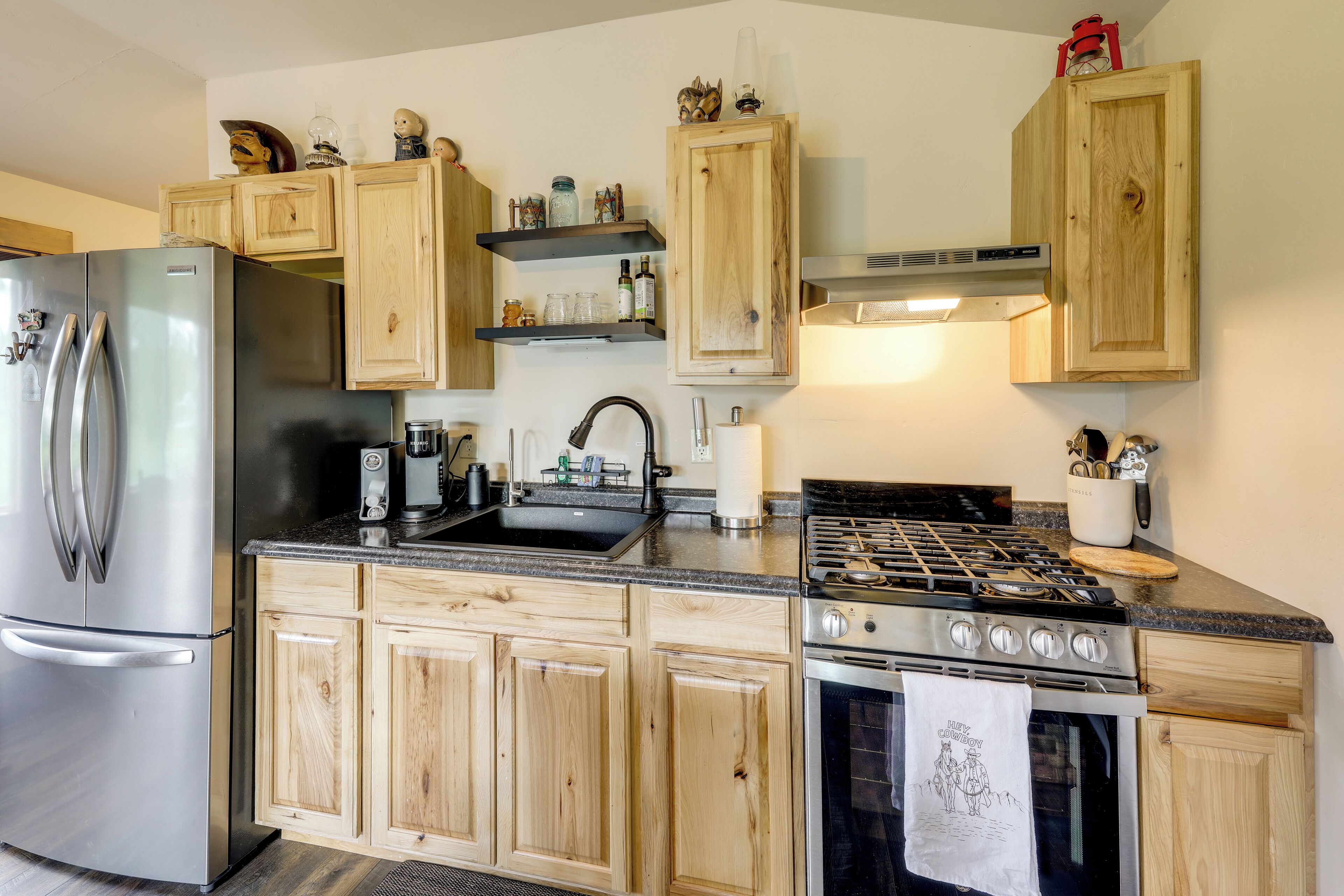 Cucina con mobili in legno, frigorifero in acciaio inossidabile, fornello e lavello.
