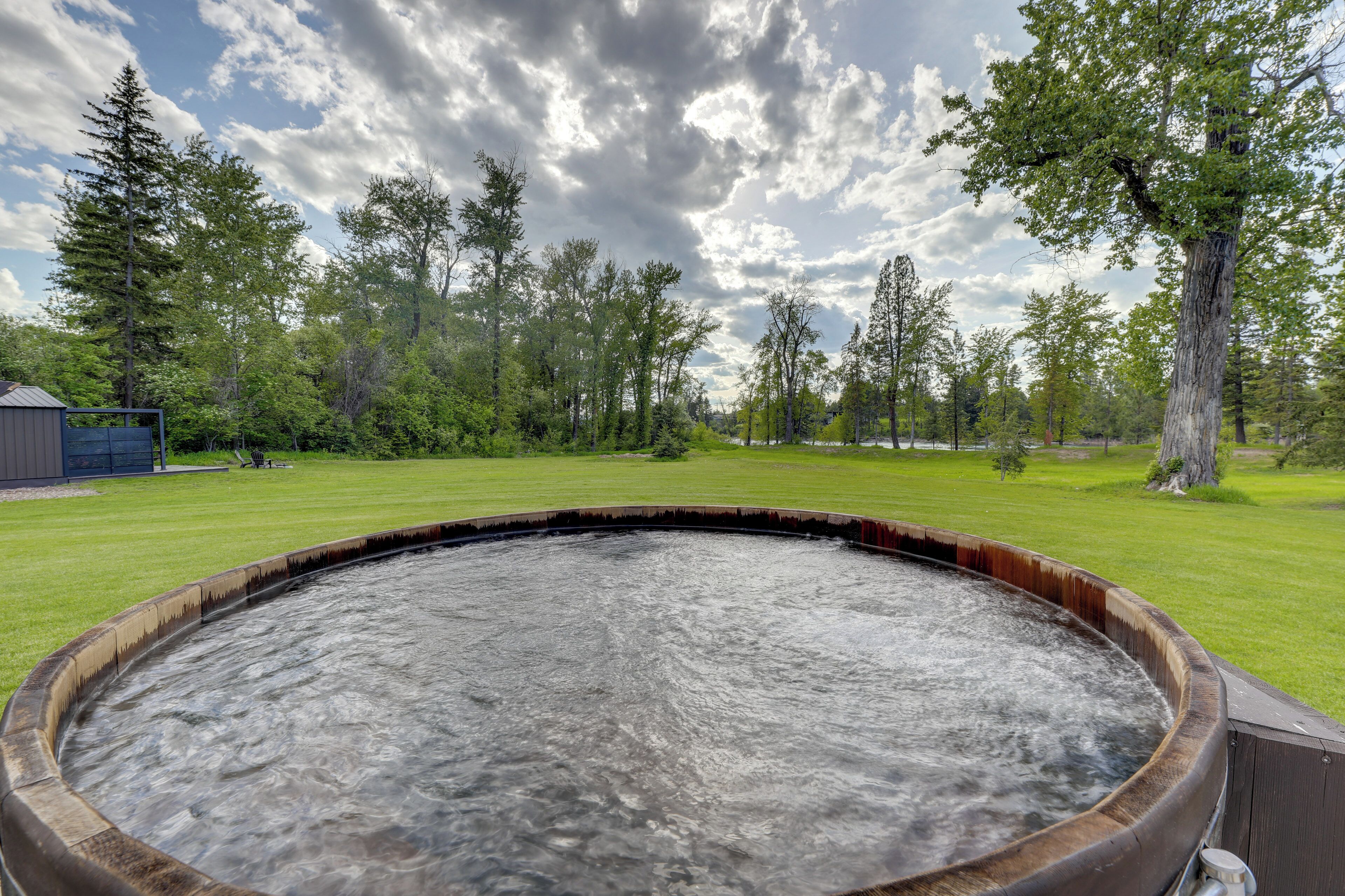 Een hottub in een grasrijk gebied, met bomen op de achtergrond.