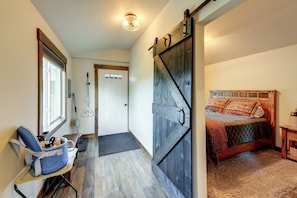 A bedroom with a bed, a wooden door, a chair, and a window.