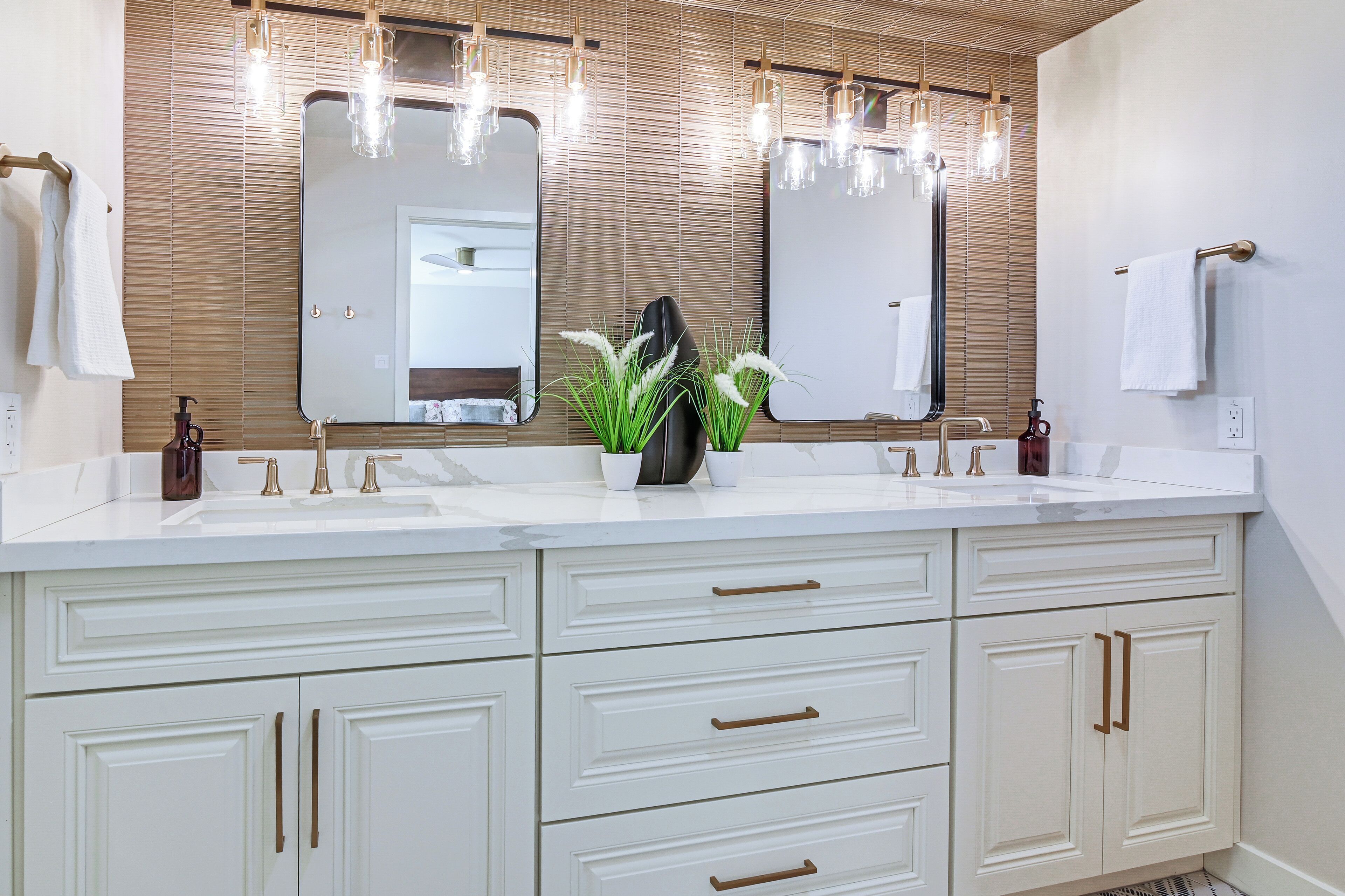 A bathroom with a large mirror, two sinks, and a vanity with drawers.