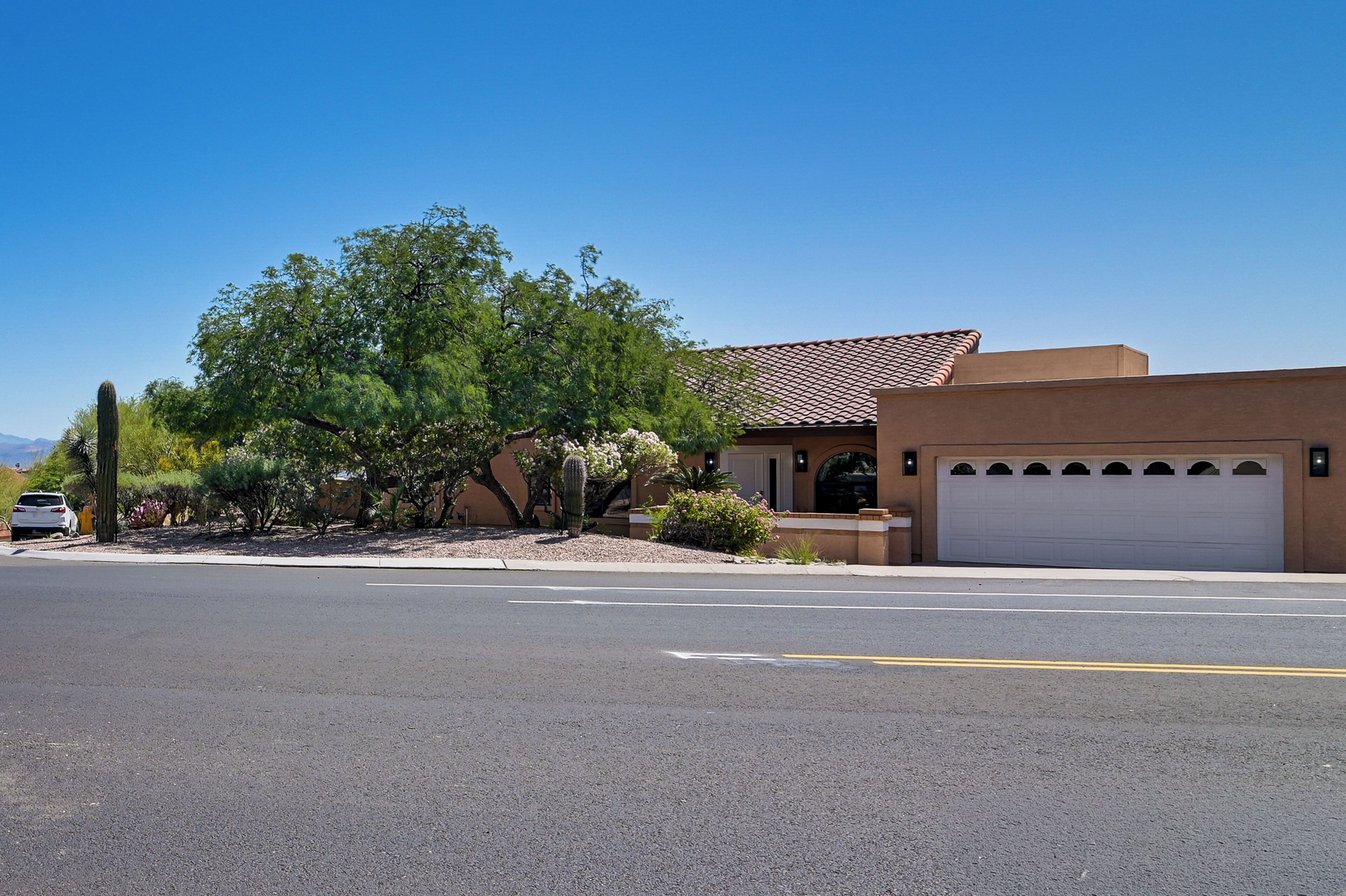A residential house with a garage, a driveway, and a tree.