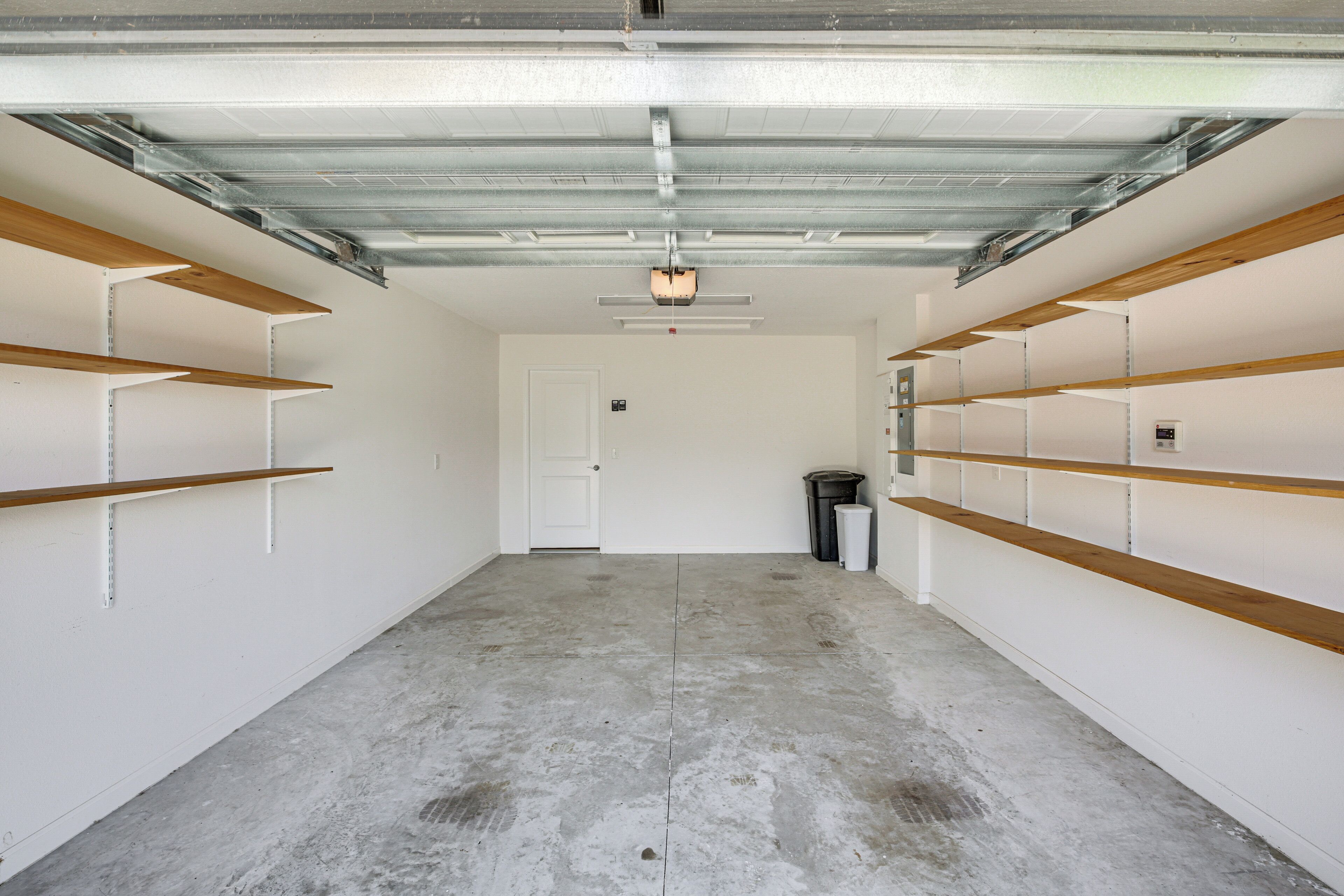 A garage with concrete floors, metal beams, and wooden shelves.
