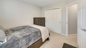 A bedroom with a bed, a dresser, a closet, and a door. - Home Near Air Force, Great Wolf, Ford Amphitheater (Colorado Springs)