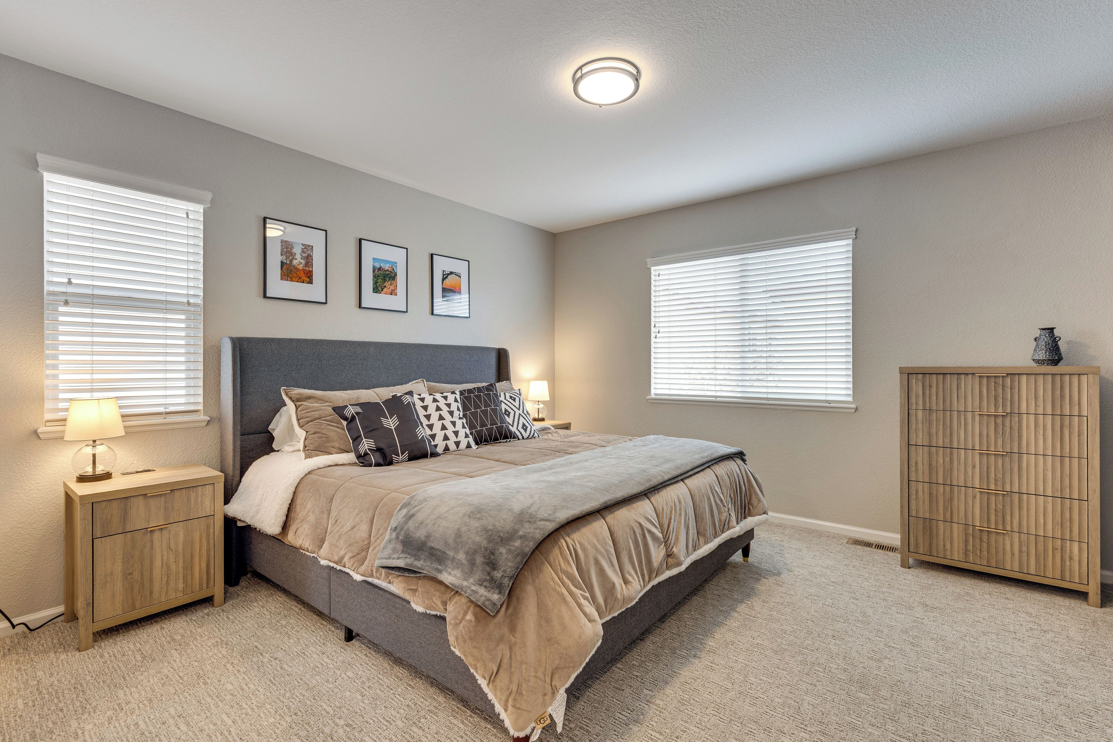 A bedroom with a bed, bedside tables, a dresser, and framed pictures on the wall.